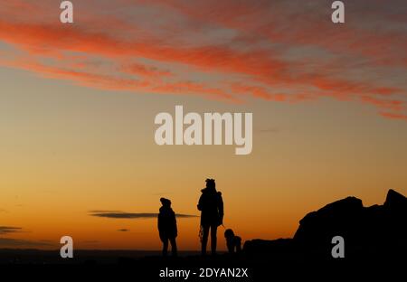 Newtown Linford, Leicestershire, Großbritannien. Dezember 2020. Wetter in Großbritannien. Hundewanderer beobachten den Sonnenaufgang am Weihnachtstag im Bradgate Park. Credit Darren Staples/Alamy Live News. Stockfoto