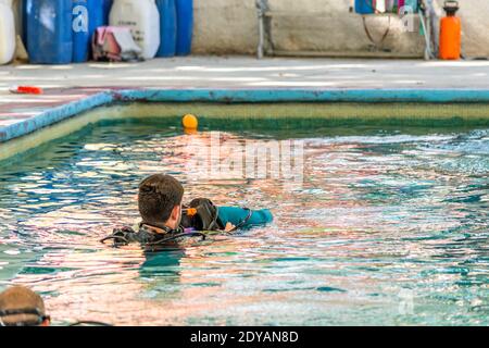 Lehrer Taucher hilft einem Schüler schwimmen während seiner Klasse Stockfoto