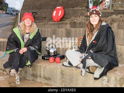 Myrtleville, Cork, Irland. Dezember 2020. Megan Mulcair und Ciara O' Connell von Carrigaline kochten einen Wasserkocher für eine heiße Tasse Tee nach dem Schwimmen am Weihnachtsmorgen in Myrtleville Beach, Co. Cork, Irland. - Credit; David Creedon / Alamy Live News Stockfoto