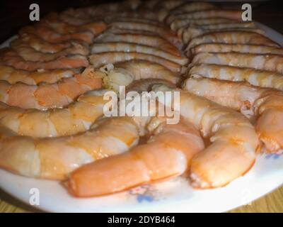 Gekochte und geschälte ganze Garnelen auf einem weißen Teller zusammen gelegt. Typische Meeresfrüchte zum Mittag- und Abendessen zu Weihnachten. Horizontale Fotografie. Stockfoto