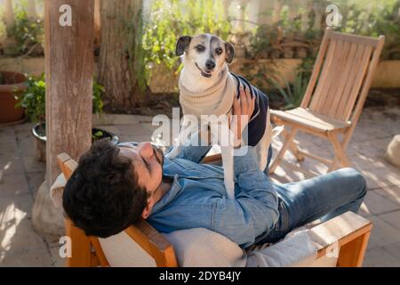 Grauer Hund ​​standing auf dem Bauch eines jungen Mannes In einem Garten Stockfoto