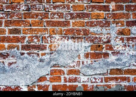 Die alte Backsteinmauer mit den Resten aus Gips Stockfoto