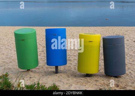 Vier bunte Mülltonnen an einem Sandstrand Stockfoto