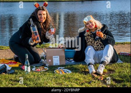 London, Großbritannien. Dezember 2020. Zwei Frauen trotzen den Elementen zu einem gesellschaftlich distanzierten Weihnachtsessen, mit allem Drum und dran, auf Clapham Common. Im Moment leben sie in zwei getrennten Haushalten, daher haben sie sich im Freien getroffen, als die plötzliche neue Coronavirus Lockdown (Tier 4) ihre ursprünglichen Pläne für das Zusammenkommen aufhörte. Kredit: Guy Bell/Alamy Live Nachrichten Stockfoto