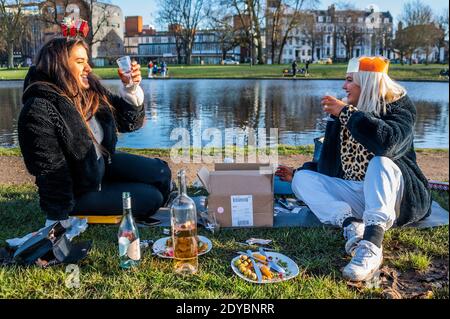 London, Großbritannien. Dezember 2020. Zwei Frauen trotzen den Elementen zu einem gesellschaftlich distanzierten Weihnachtsessen, mit allem Drum und dran, auf Clapham Common. Im Moment leben sie in zwei getrennten Haushalten, daher haben sie sich im Freien getroffen, als die plötzliche neue Coronavirus Lockdown (Tier 4) ihre ursprünglichen Pläne für das Zusammenkommen aufhörte. Kredit: Guy Bell/Alamy Live Nachrichten Stockfoto