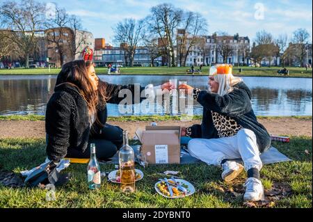 London, Großbritannien. Dezember 2020. Zwei Frauen trotzen den Elementen zu einem gesellschaftlich distanzierten Weihnachtsessen, mit allem Drum und dran, auf Clapham Common. Im Moment leben sie in zwei getrennten Haushalten, daher haben sie sich im Freien getroffen, als die plötzliche neue Coronavirus Lockdown (Tier 4) ihre ursprünglichen Pläne für das Zusammenkommen aufhörte. Kredit: Guy Bell/Alamy Live Nachrichten Stockfoto