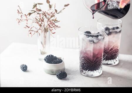 Erfrischende Blackberry Lemonade mit Eis in Kristallgläsern auf weißem Hintergrund Stockfoto