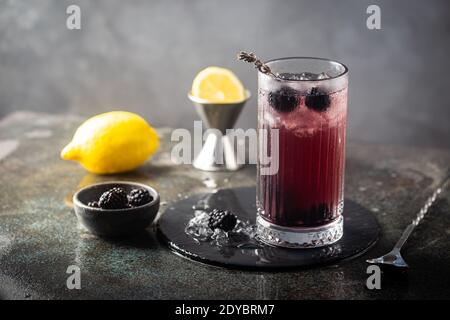 Erfrischende Blackberry Lemonade mit Eis in Kristallgläsern auf grauem Hintergrund Stockfoto