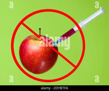 Genetisch modifizierter roter Apfel mit Spritzen auf grünem Hintergrund.Stoppen Sie die Injektion von GVO in Apfel, Fruchtkonzept minimal Stockfoto