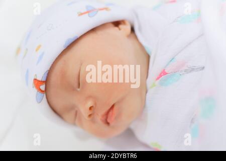 Neugeborenes chinesisches Baby Mädchen weniger als einen Monat alt schlafen solide, warm in Musselin Tuch eingewickelt. Stockfoto