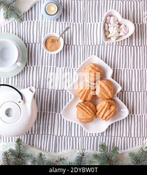 Kreative Xmas Tischaufstellung für Tee. Draufsicht auf Eclare, Kuchen backen. Teller mit Kuchen in Form von Weihnachtsbaum. Tannenzweige mit leichter Girlande Stockfoto