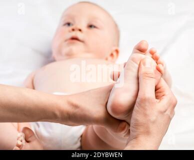 Fünf Monate Baby erhalten Massage-Therapie in der Kinderklinik. Der manuelle Therapeut manipuliert den Fuß von Kindern Stockfoto