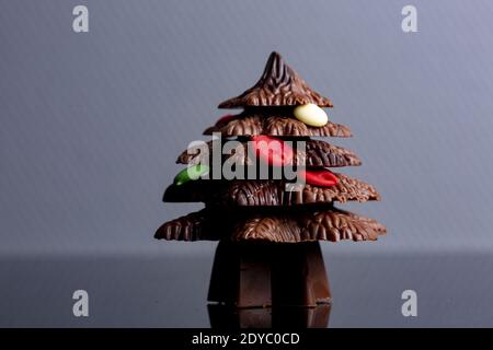 Bläulich grau leerer Raum mit einem einzigen Weihnachtsbaum geformt Schokolade mit Süßigkeiten als Dekoration mit Reflexion in Die dunkle Oberfläche im f Stockfoto