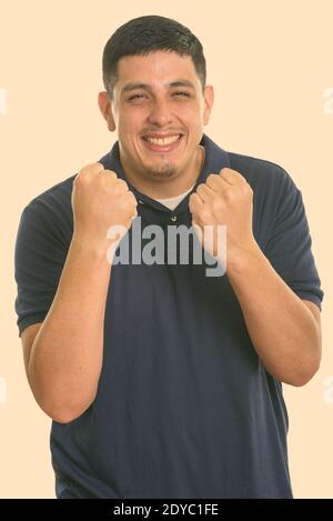 Studio shot der Jungen glücklich Hispanic Mann lächelnd, während sie aufgeregt Stockfoto
