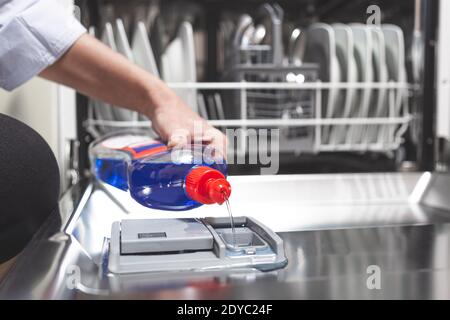 Füllen Sie den Geschirrspüler mit Glanzflüssigkeit aus nächster Nähe in die Spülmaschine-Box. Hausarbeit Konzept. Stockfoto