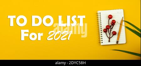 Minimal Design to do Liste für neue 2021 mit einem Notebook auf dem Desktop mit einem gelben Hintergrund und Zimmerpflanzen, flach Lay Konzept Foto Stockfoto