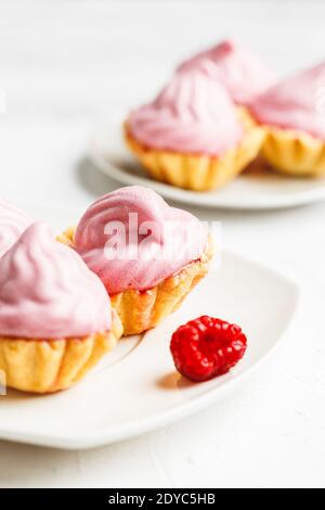 Mini-Kuchen Körbe mit Himbeer-Sahne auf weißem Teller serviert Stockfoto