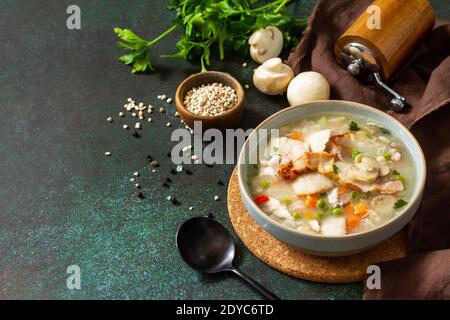 Gesunde Ernährung. Hausgemachte herzhafte Suppe mit Müsli, Speck und Pilzen auf dunklem Steingrund. Speicherplatz kopieren. Stockfoto