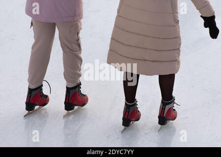 Paar Schlittschuh auf der Eisbahn. Nahaufnahme des unteren Körperteils, der Beine und der Schlittschuhe. Schwenktechnik Stockfoto