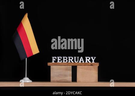 Holzkalender Februar mit deutscher Flagge auf schwarzem Hintergrund. Feiertage der Deutschen im Februar Stockfoto