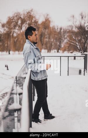 Hispanic Brünette Mann mit Bart in Jeansjacke im Winter mitten im Schnee. Männer Street Fashion Casual Style 2021 Stockfoto