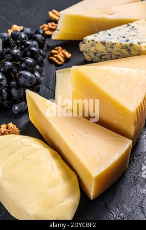 Verschiedene Arten von köstlichem Käse mit Walnüssen und Trauben. Schwarzer Hintergrund. Draufsicht Stockfoto