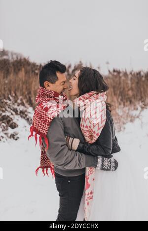 Hochzeitspaar läuft im Schnee liegend lachen Spaß spielen Schneebälle Stockfoto