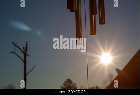 Die Sonne geht hinter hängenden Windspielen auf Stockfoto