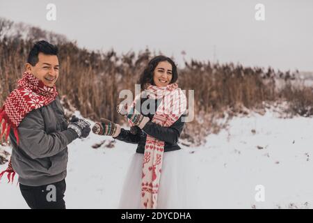 Hochzeitspaar läuft im Schnee liegend lachen Spaß spielen Schneebälle Stockfoto