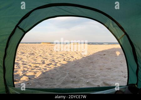 Blick von der Innenseite des Zeltes auf Meer und Sandstrand. Camping am Meer. Stockfoto