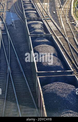 Die schwarze Kohle in den Zugwaggons auf den Schienen wird bewegt Zur nächsten Entladestelle in der Logistik Stockfoto