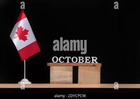 Holzkalender Oktober mit kanadischer Flagge auf schwarzem Hintergrund. Urlaub Kanada im Herbst. Stockfoto