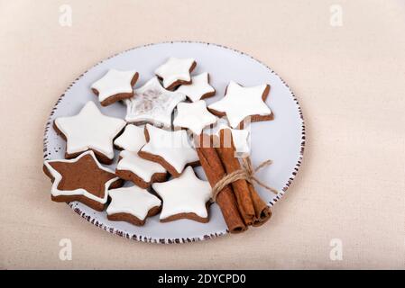 Glasierte Lebkuchensterne und Zimtstangen auf dem Teller. Weihnachtsplätzchen. Stockfoto