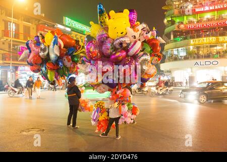 Vietnam Hanoi Ballon-Händler auf einer belebten Straße in der Nacht Stockfoto