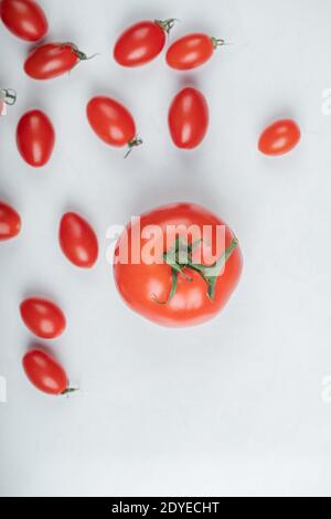 Tomate bedeckt mit Kirschtomaten auf weißem Hintergrund Stockfoto