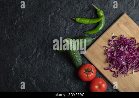 Gemüsemischung. Gehackter Kohl, Gurke, Tomate und Pipette auf schwarzem Hintergrund Stockfoto