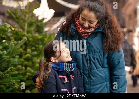 Kleines Mädchen und ihre Mutter suchen einander im Freien In einer Innenstadt zur Weihnachtszeit Stockfoto