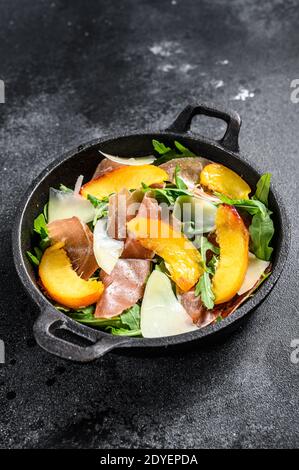 Salat mit Prosciutto, Pfirsich und Rucola. Kalte Snacks. Schwarzer Hintergrund. Draufsicht. Stockfoto