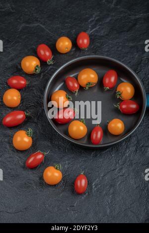 Bunte Kirschtomaten in der Pfanne auf schwarzem Hintergrund Stockfoto