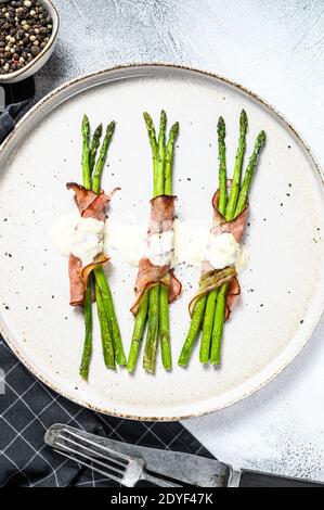 Gegrillter Bio-Spargel in Schweinebackschinken eingewickelt. Grauer Hintergrund. Draufsicht Stockfoto