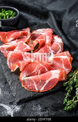 Italienischer Speck Pancetta Piacentina. Schweinefleisch. Schwarzer Hintergrund. Draufsicht Stockfoto