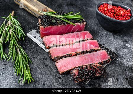 Seltene Ahi Thunfisch-Steak Scheiben auf einem Fleischspalter. Schwarzer Hintergrund. Draufsicht Stockfoto