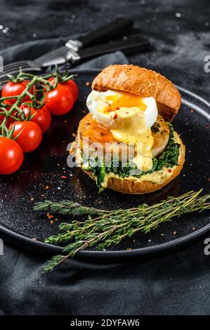 Hausgemachter Fisch Burger mit Kabeljaufilet, Ei und Spinat auf einem Brioche-Brötchen. Schwarzer Hintergrund. Draufsicht Stockfoto