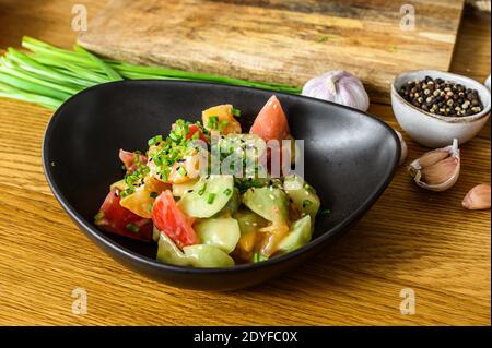 Ein Koch in schwarzen Handschuhen bereitet einen vegetarischen Gemüsesalat zu. Konzept der Küche gesunde Bio-Lebensmittel Stockfoto