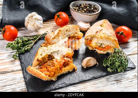 Baguette gefüllt mit Auberginen, Tomaten und Käse. Ein köstliches vegetarisches Mittagessen, leckere Snacks, hausgemachtes Sandwich. Grauer Hintergrund. Draufsicht Stockfoto