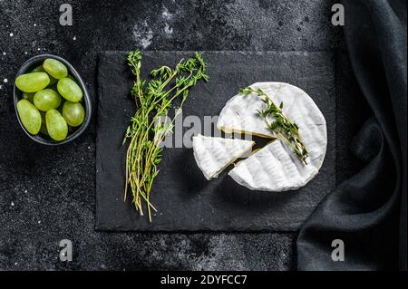 Französischer Camembert-Käse mit Trauben. Schwarzer Hintergrund. Draufsicht Stockfoto