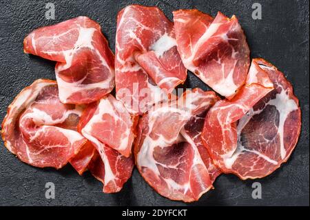 Italienischer Speck Pancetta Piacentina. Schweinefleisch. Schwarzer Hintergrund. Draufsicht Stockfoto