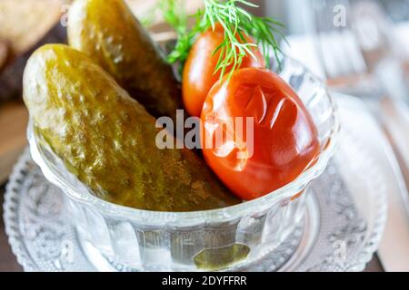 Gesalzene marinierte Gurken und Tomaten mit Dill in der transparenten Glasschüssel. Köstlicher traditioneller Snack. Stockfoto