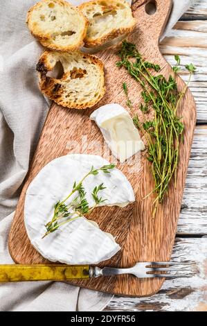 Französischer Camembert-Käse mit Trauben auf Holzschneidebrett. Weißer Hintergrund. Draufsicht Stockfoto