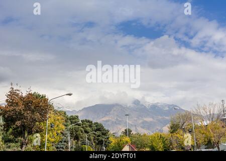 Winter Teheran Straßenansicht in Teheran International Exhibition Centre mit Schneebedeckte Alborz Berge gegen bewölkten Himmel auf Hintergrund Stockfoto